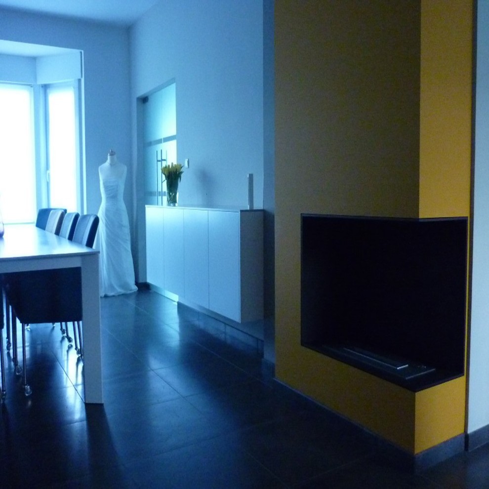 Cette image montre un grand bureau minimaliste de type studio avec un mur jaune, une cheminée standard, un manteau de cheminée en pierre et un bureau intégré.