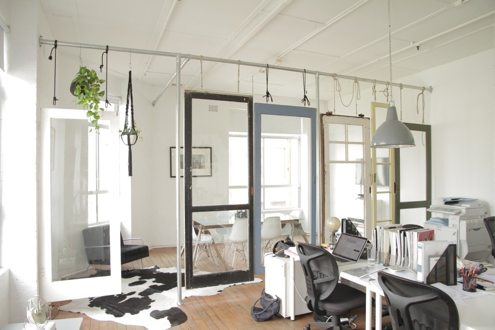 Idée de décoration pour un grand bureau bohème de type studio avec un mur blanc, un sol en bois brun et un bureau indépendant.
