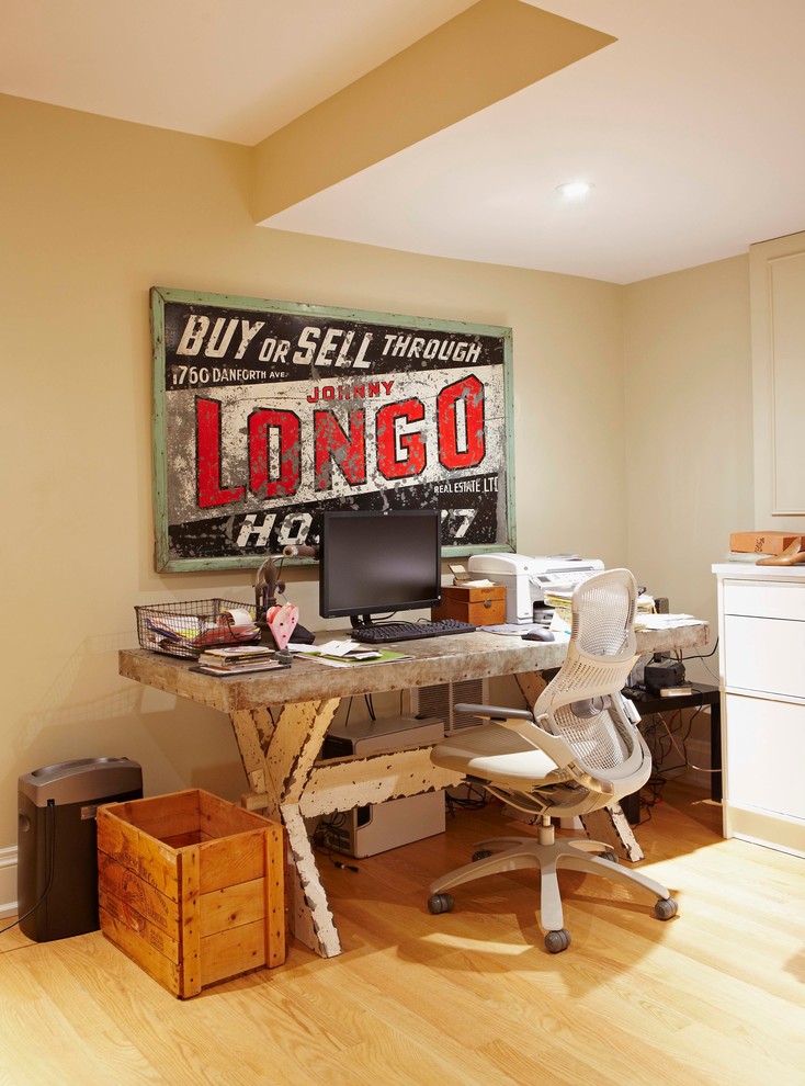 Ejemplo de despacho urbano pequeño con paredes beige, suelo de madera clara y escritorio independiente