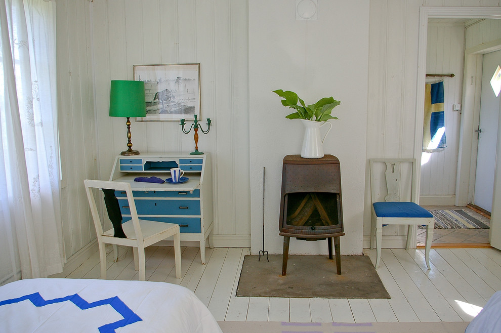Foto på ett lantligt arbetsrum, med vita väggar, målat trägolv, en öppen vedspis, en spiselkrans i metall och vitt golv