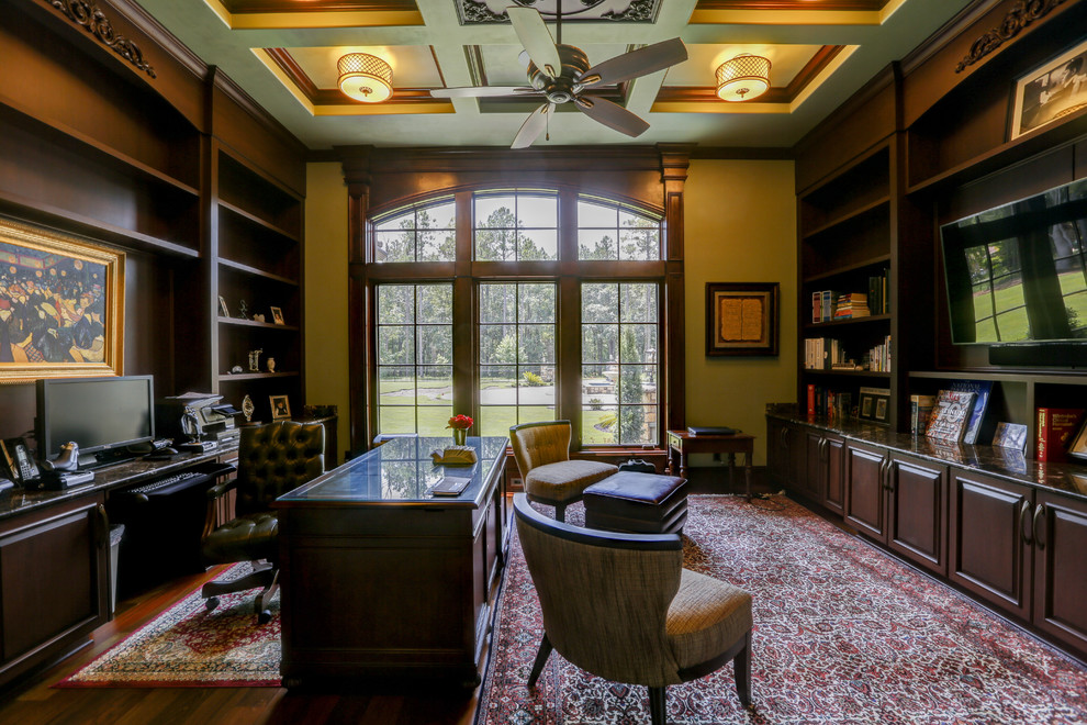 Imagen de despacho tradicional grande con paredes verdes, suelo de madera en tonos medios y escritorio independiente