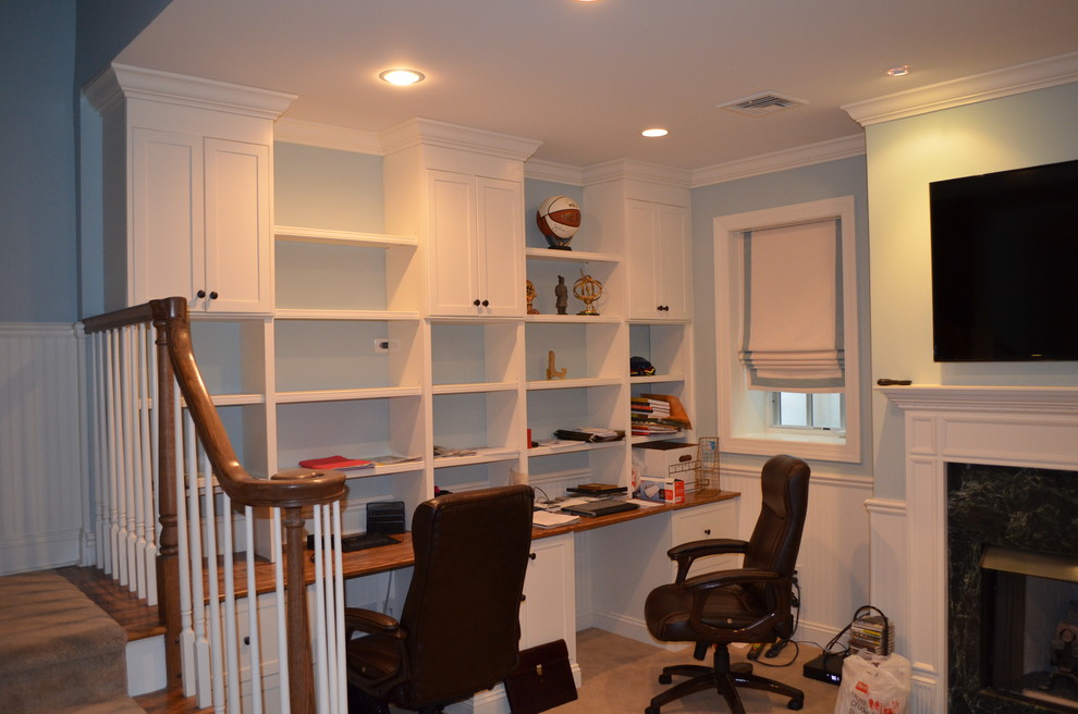 Modelo de despacho clásico renovado de tamaño medio con paredes azules, moqueta, todas las chimeneas, escritorio empotrado y marco de chimenea de baldosas y/o azulejos