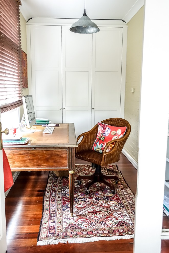 Modelo de despacho campestre pequeño con paredes amarillas, suelo de madera en tonos medios y escritorio independiente
