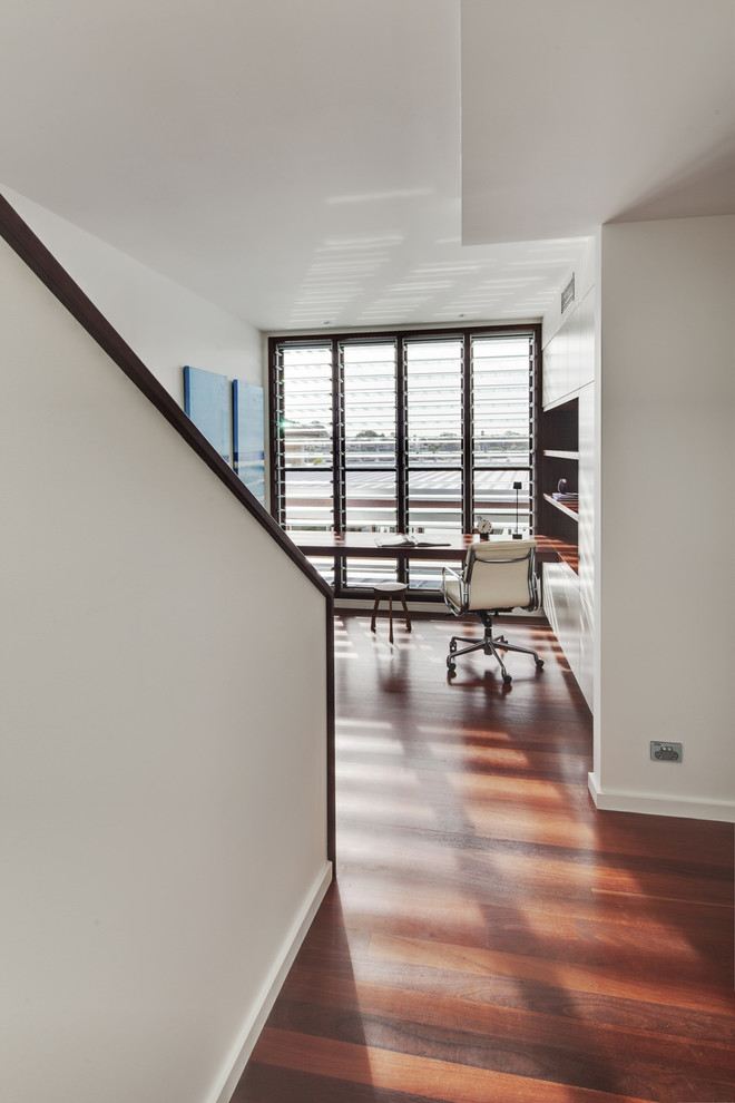 Mittelgroßes Modernes Arbeitszimmer ohne Kamin mit Arbeitsplatz, weißer Wandfarbe, braunem Holzboden und Einbau-Schreibtisch in Sydney