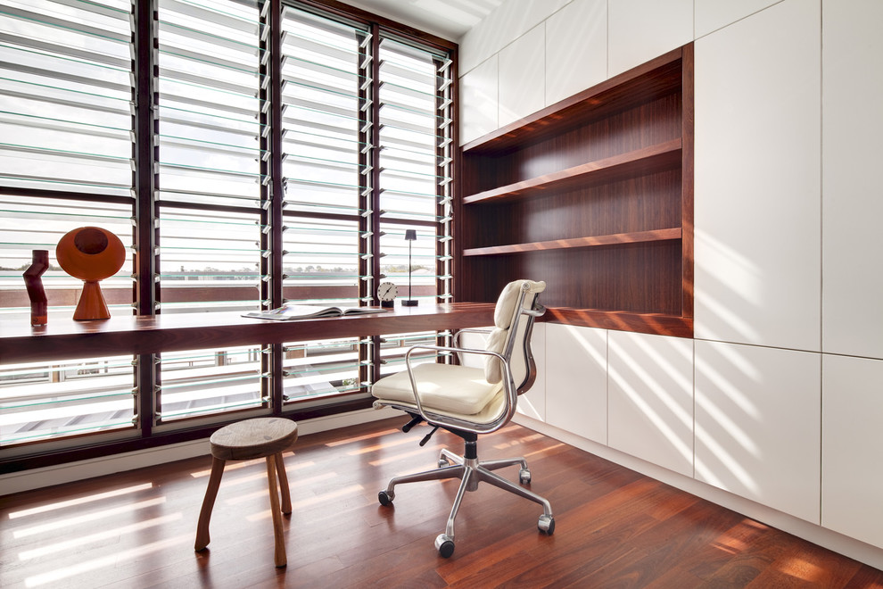 Cette photo montre un bureau moderne de taille moyenne avec un mur blanc, un sol en bois brun, aucune cheminée et un bureau intégré.