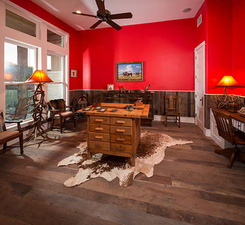 Rustikales Arbeitszimmer ohne Kamin mit Arbeitsplatz, roter Wandfarbe, braunem Holzboden und freistehendem Schreibtisch in Austin