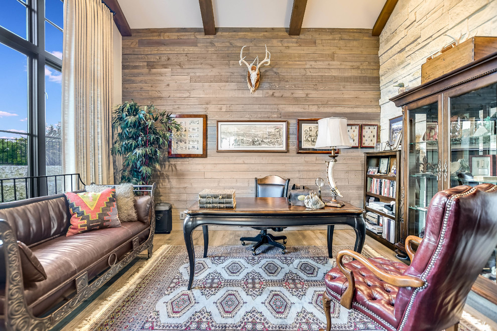Rustikales Lesezimmer mit brauner Wandfarbe, braunem Holzboden, freistehendem Schreibtisch und braunem Boden in Austin