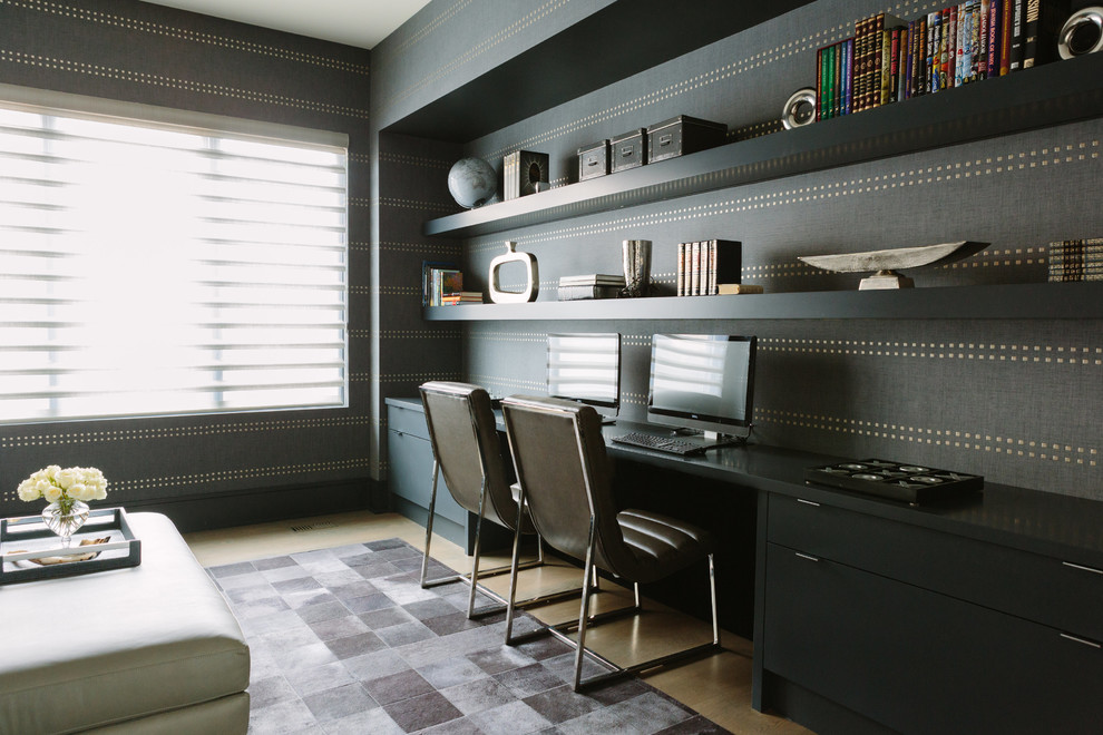 Bild på ett stort funkis hemmabibliotek, med mellanmörkt trägolv, ett inbyggt skrivbord, brunt golv och grå väggar