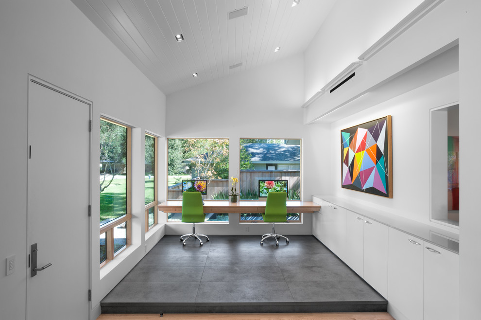 Immagine di uno studio minimalista con pareti bianche, pavimento in gres porcellanato, scrivania incassata e pavimento grigio