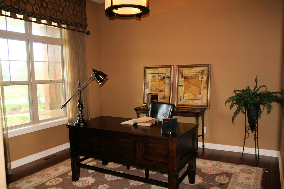 Arbeitszimmer mit Arbeitsplatz, beiger Wandfarbe, dunklem Holzboden und freistehendem Schreibtisch in Milwaukee