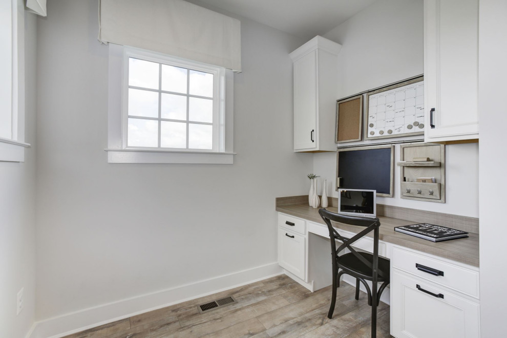 Inredning av ett klassiskt litet arbetsrum, med vita väggar, ett inbyggt skrivbord, laminatgolv och grått golv