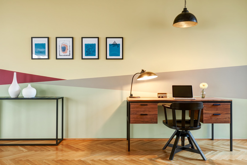 Cette photo montre un bureau tendance de taille moyenne avec un mur multicolore, parquet clair, un bureau indépendant, un sol beige et aucune cheminée.