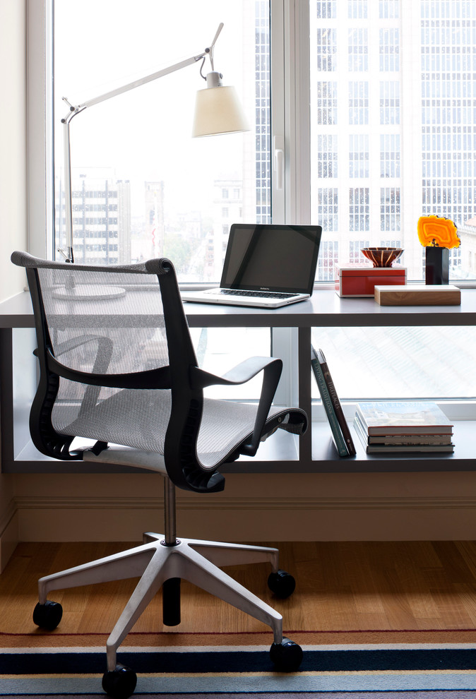 Ejemplo de despacho minimalista de tamaño medio con suelo de madera en tonos medios, escritorio independiente y paredes grises