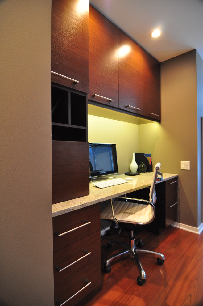 Cette image montre un petit bureau design avec un mur vert, un sol en bois brun et un bureau intégré.