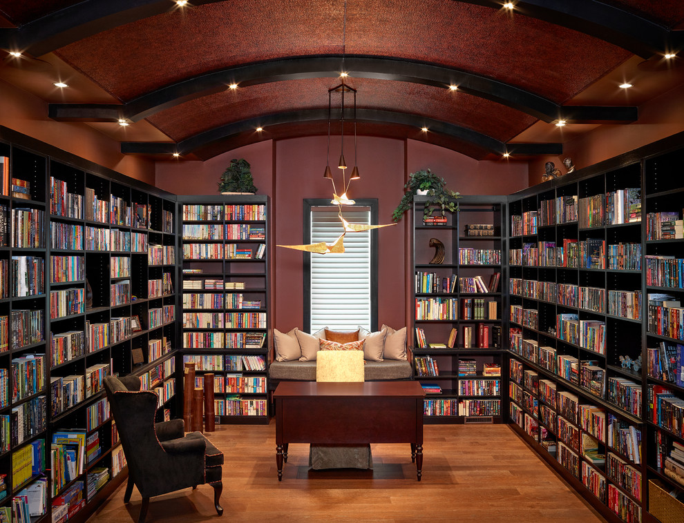 Esempio di un grande studio tradizionale con libreria, pareti rosse, nessun camino, pavimento in legno massello medio, scrivania autoportante e pavimento arancione