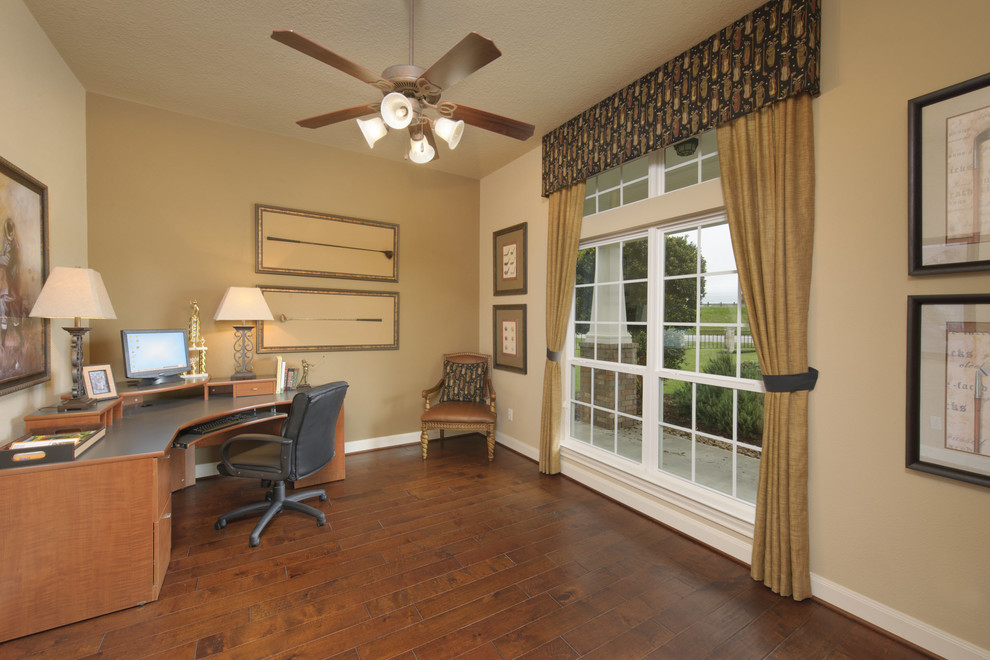 Imagen de despacho tradicional de tamaño medio sin chimenea con paredes beige, suelo de madera en tonos medios, escritorio independiente y suelo marrón