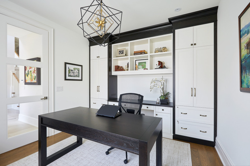 Example of a mid-sized transitional freestanding desk medium tone wood floor and brown floor home office library design in Toronto with white walls