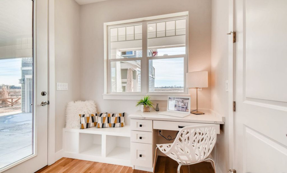 Idée de décoration pour un petit bureau atelier craftsman avec un mur blanc, parquet clair, un bureau intégré et un sol marron.
