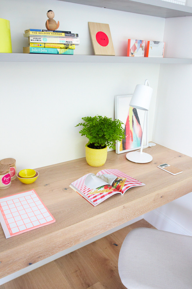 This is an example of a small scandi study in Melbourne with white walls, light hardwood flooring and a built-in desk.