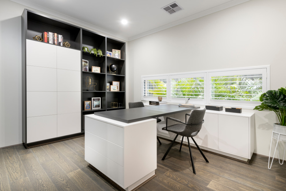 Imagen de despacho actual sin chimenea con paredes blancas, suelo de madera en tonos medios, escritorio independiente y suelo marrón