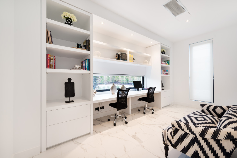 Idéer för ett stort modernt hemmabibliotek, med vita väggar, ett inbyggt skrivbord och grått golv