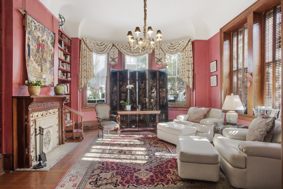 This is an example of a medium sized eclectic home office in New Orleans with a reading nook, red walls, medium hardwood flooring, a standard fireplace, a tiled fireplace surround and a freestanding desk.
