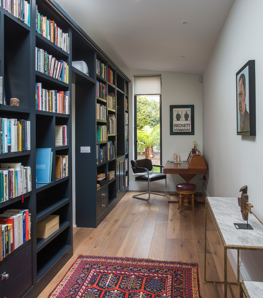 Ejemplo de despacho clásico renovado sin chimenea con suelo de madera en tonos medios, escritorio independiente, biblioteca y paredes grises