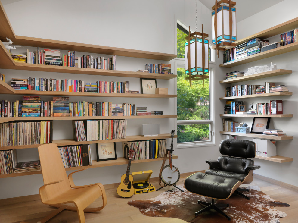 Foto på ett mellanstort funkis arbetsrum, med ett bibliotek och vita väggar