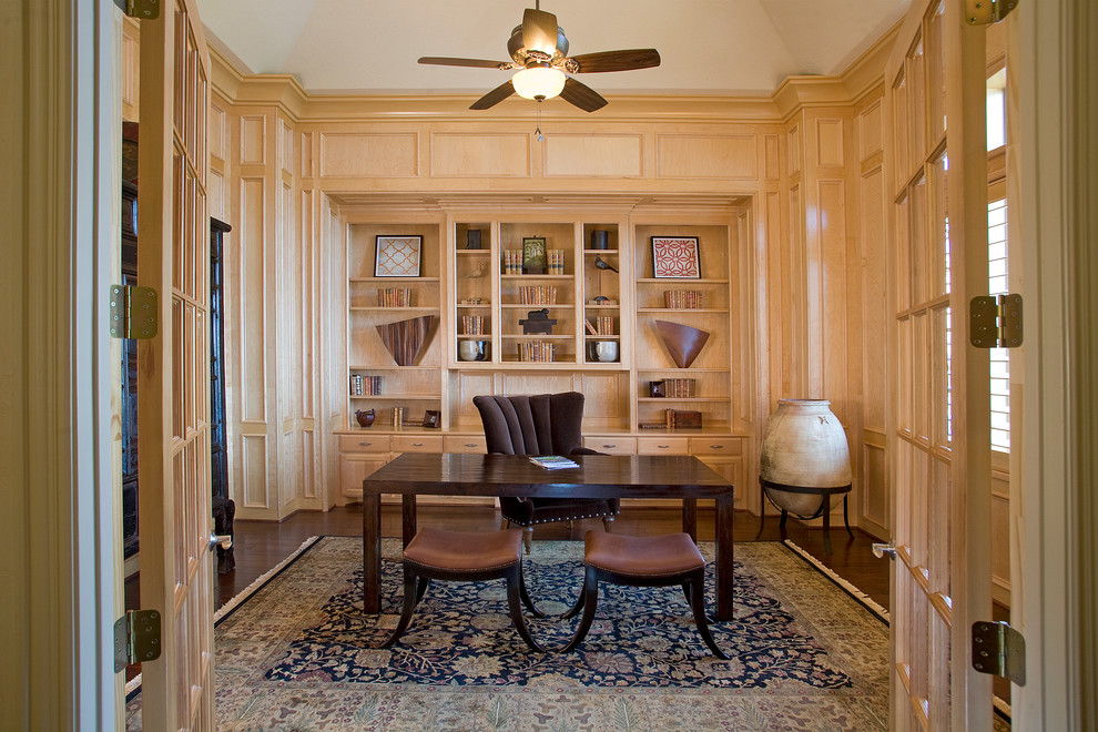 Klassisches Arbeitszimmer mit dunklem Holzboden, freistehendem Schreibtisch und braunem Boden in Houston