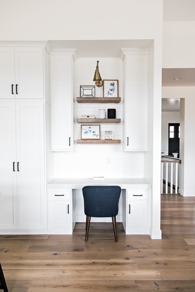 Ejemplo de despacho campestre pequeño sin chimenea con paredes blancas, suelo de madera en tonos medios, escritorio empotrado y suelo marrón