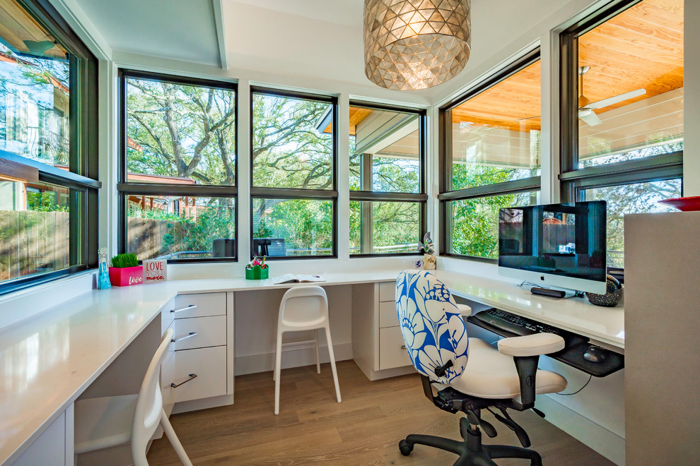 Large elegant built-in desk medium tone wood floor and beige floor home studio photo in Austin with beige walls