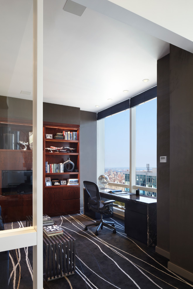 Großes Modernes Arbeitszimmer ohne Kamin mit grauer Wandfarbe, Teppichboden, freistehendem Schreibtisch, Arbeitsplatz und schwarzem Boden in New York
