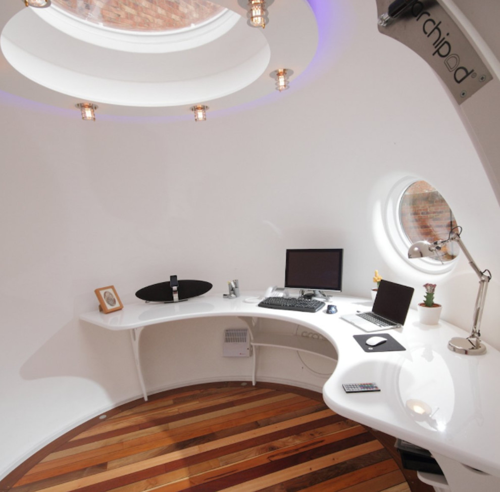 Foto de estudio actual de tamaño medio con paredes blancas, suelo de madera en tonos medios y escritorio empotrado