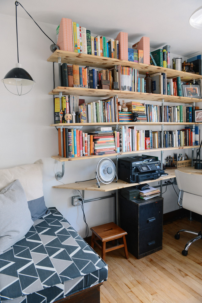 Foto på ett litet industriellt hemmabibliotek, med vita väggar, ljust trägolv och ett inbyggt skrivbord