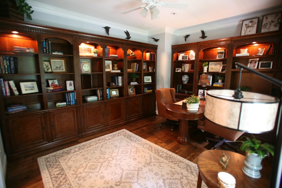 Modelo de despacho clásico pequeño con paredes azules, suelo de madera en tonos medios, escritorio independiente y suelo marrón