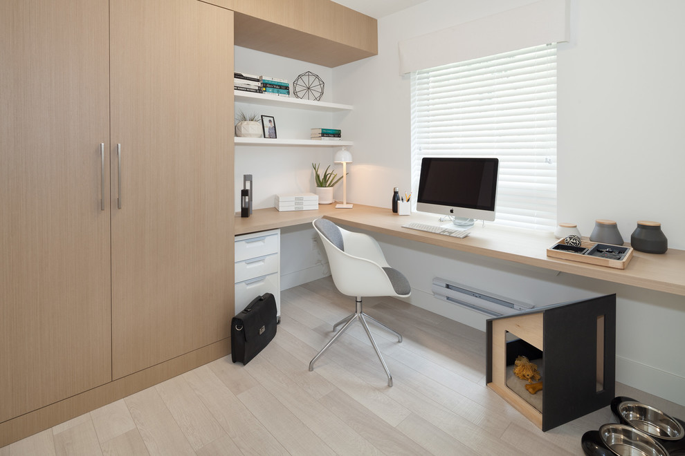 Diseño de despacho actual de tamaño medio con paredes blancas, suelo de madera clara y escritorio empotrado