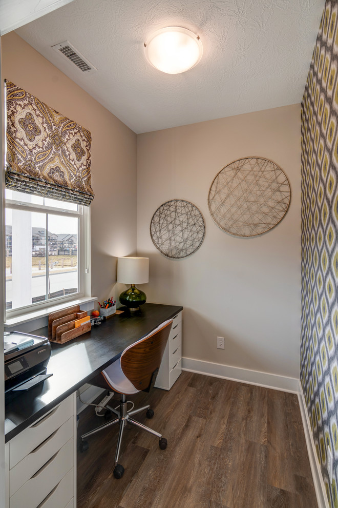 Ejemplo de despacho pequeño con paredes beige, suelo vinílico, escritorio independiente y suelo marrón