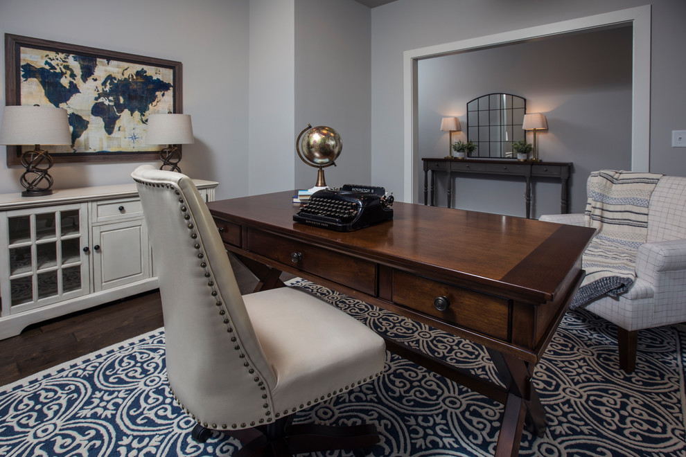 Cette photo montre un grand bureau craftsman avec un mur gris, parquet foncé, un bureau indépendant et un sol marron.