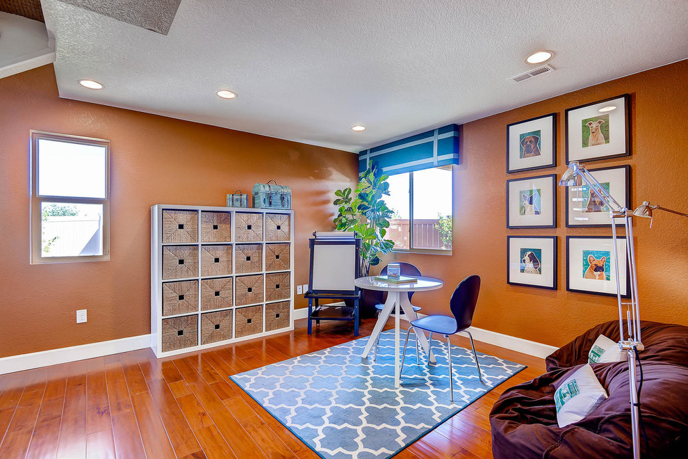デンバーにあるトランジショナルスタイルのおしゃれなホームオフィス・書斎 (オレンジの壁、無垢フローリング、暖炉なし、自立型机) の写真