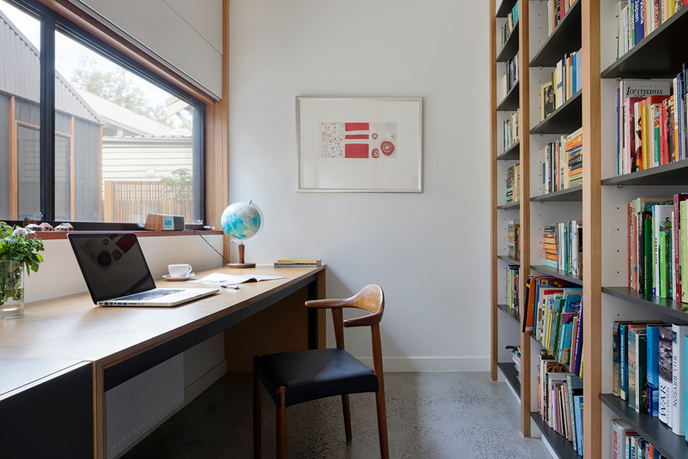 Inspiration för moderna hemmabibliotek, med vita väggar, betonggolv och ett inbyggt skrivbord
