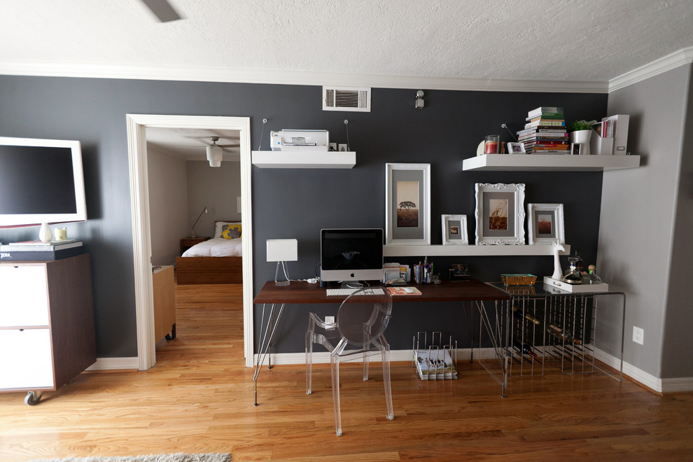 Diseño de despacho industrial con paredes negras, suelo de madera en tonos medios y escritorio independiente