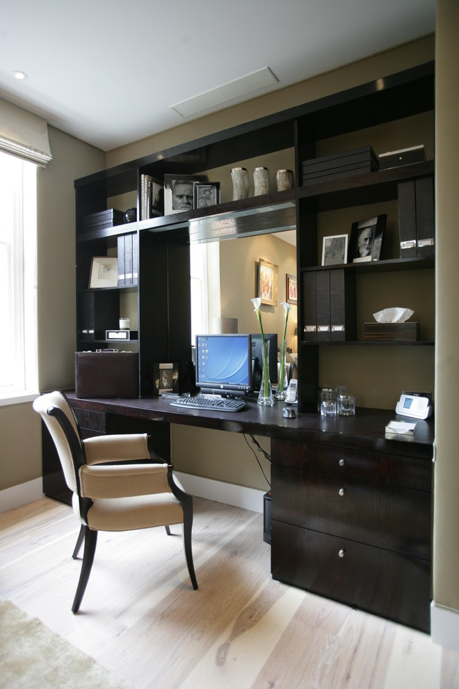 This is an example of a small contemporary study in London with beige walls, light hardwood flooring and a built-in desk.