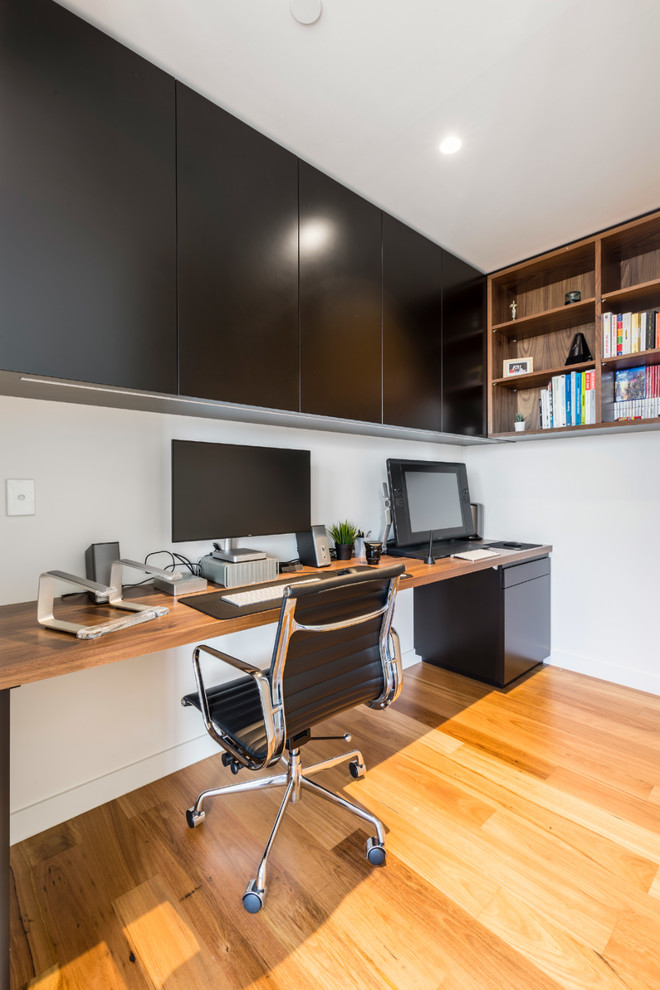 Foto de despacho contemporáneo de tamaño medio con paredes blancas, suelo de madera en tonos medios y escritorio empotrado