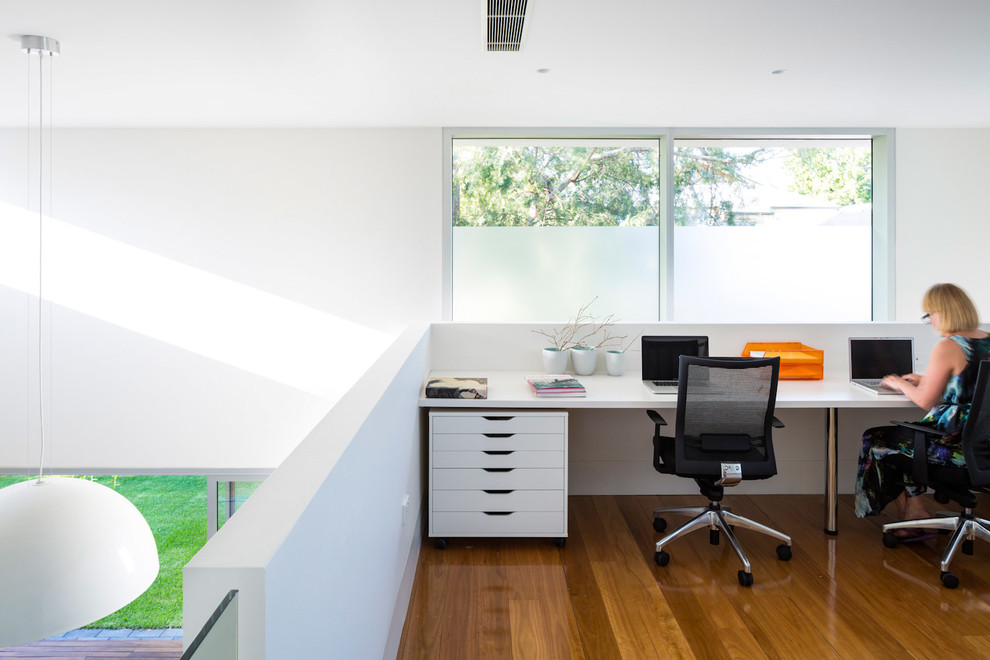 Свежая идея для дизайна: рабочее место в современном стиле с белыми стенами, паркетным полом среднего тона и встроенным рабочим столом - отличное фото интерьера