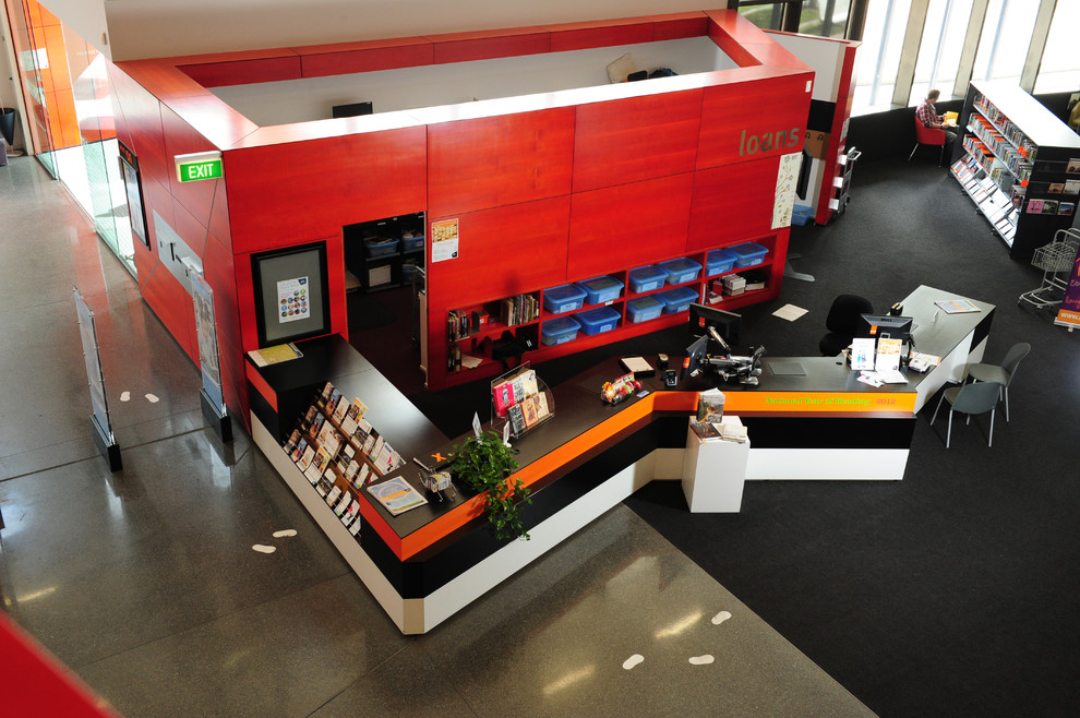 Großes Rustikales Lesezimmer mit roter Wandfarbe, Betonboden, Einbau-Schreibtisch und grauem Boden in Sonstige
