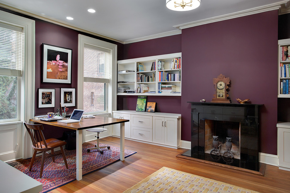Exempel på ett stort klassiskt arbetsrum, med lila väggar, mellanmörkt trägolv, en standard öppen spis, en spiselkrans i sten och ett fristående skrivbord