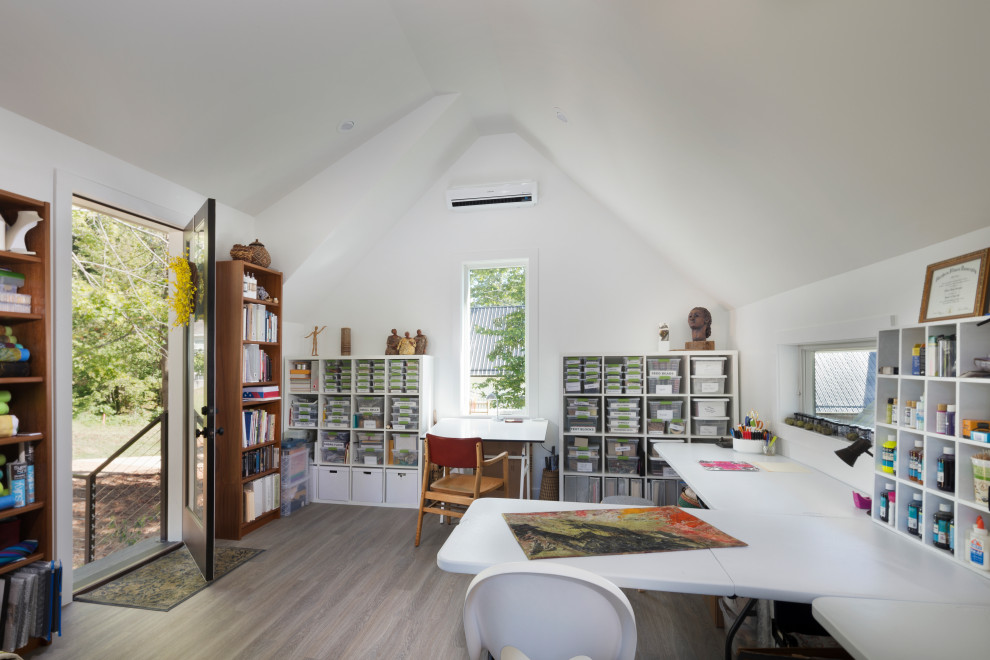 Imagen de estudio de estilo de casa de campo grande con paredes blancas, suelo de madera clara, escritorio independiente y suelo gris