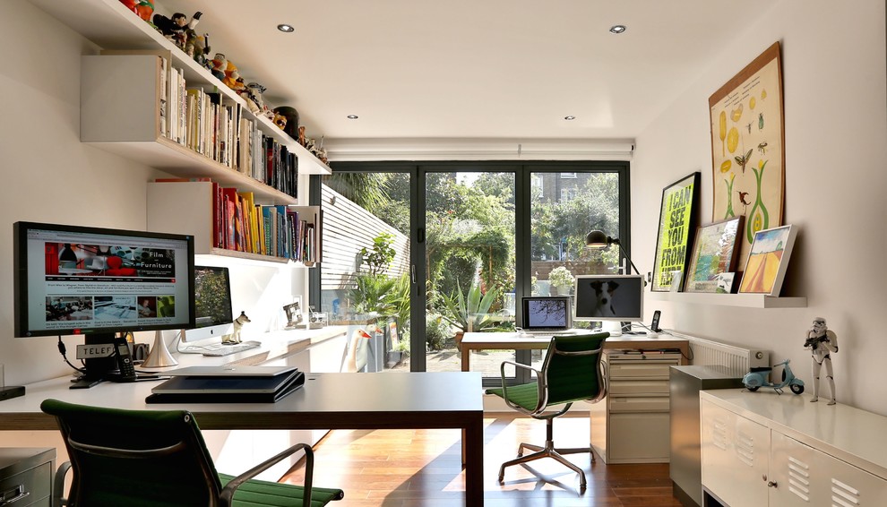 Imagen de estudio bohemio de tamaño medio con paredes blancas, suelo de madera oscura y escritorio independiente