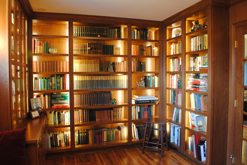Cette photo montre un bureau chic de taille moyenne avec une bibliothèque ou un coin lecture, un sol en bois brun et aucune cheminée.
