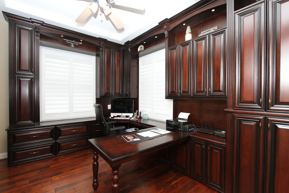 Imagen de despacho tradicional grande con paredes beige, suelo de madera oscura, escritorio empotrado y suelo marrón